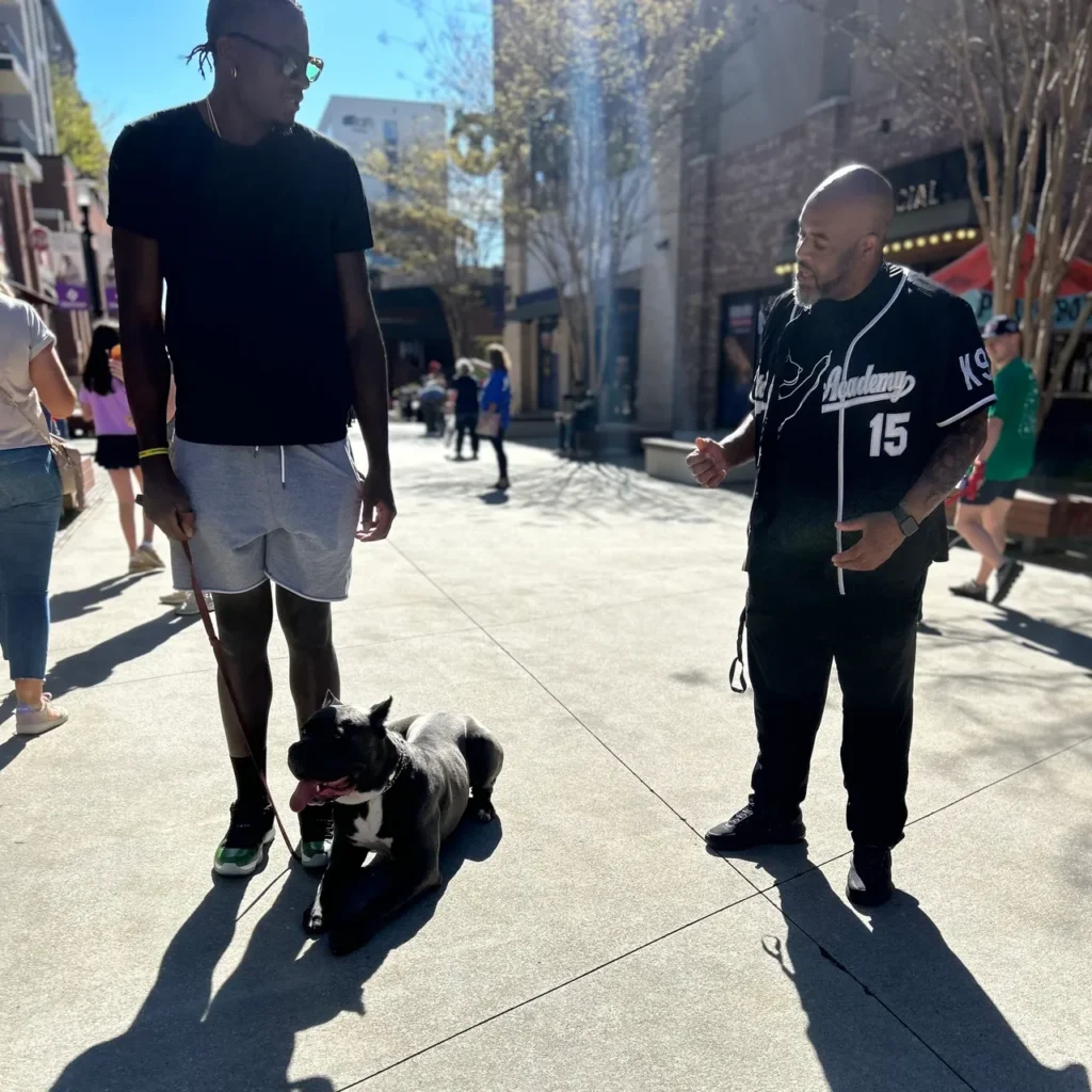 Professional basketball players interacting with a dog in a public space, showcasing Off The Chain K9 Academy's training and community involvement.