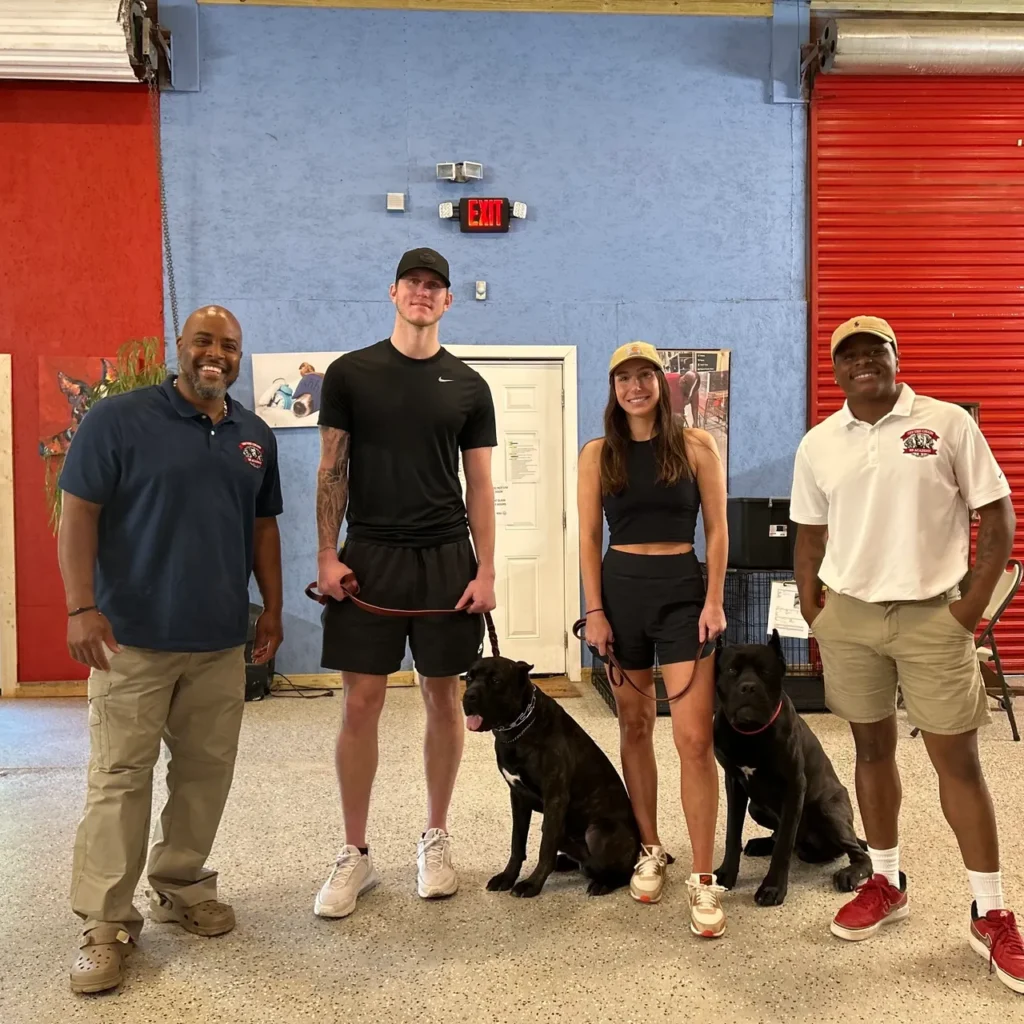 Veteran-owned OTCK9 Academy staff with professional athletes and dogs, showcasing commitment to effective dog training and community engagement.