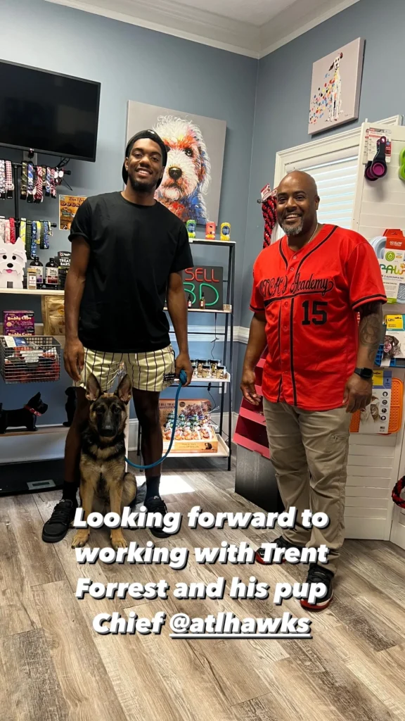 Trent Forrest, professional basketball player, posing with a German Shepherd dog named Chief in a dog training facility, showcasing the veteran-owned Off The Chain K9 Academy's services.