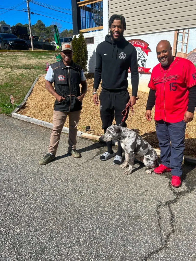 Veteran trainers and professional basketball players with a dog at Off The Chain K9 Academy, showcasing the academy's commitment to effective dog training and community engagement.