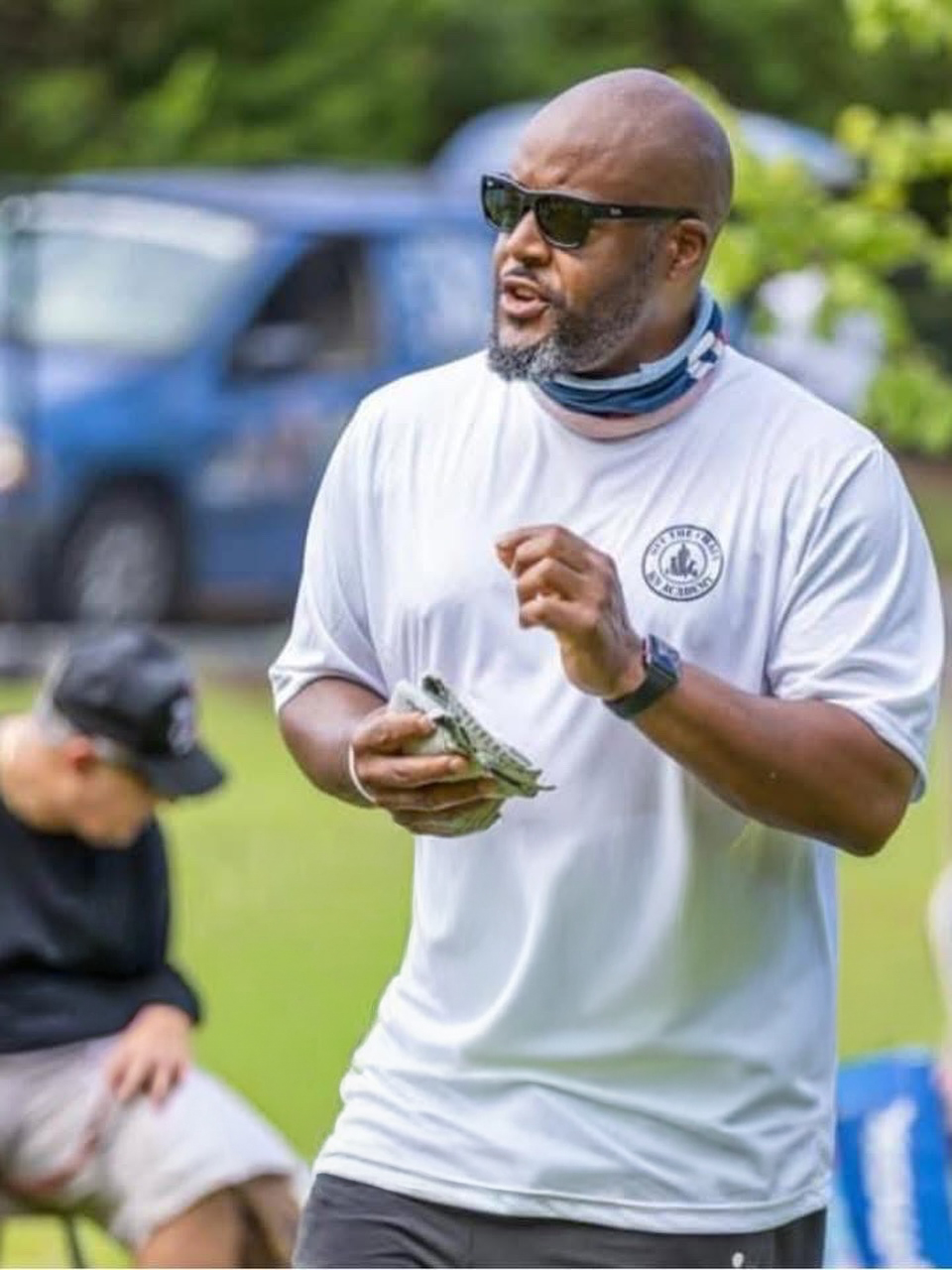 About 5 Dog trainer demonstrating techniques at OTCK9 Academy, wearing sunglasses and a white shirt, with a focus on communication and training methods.